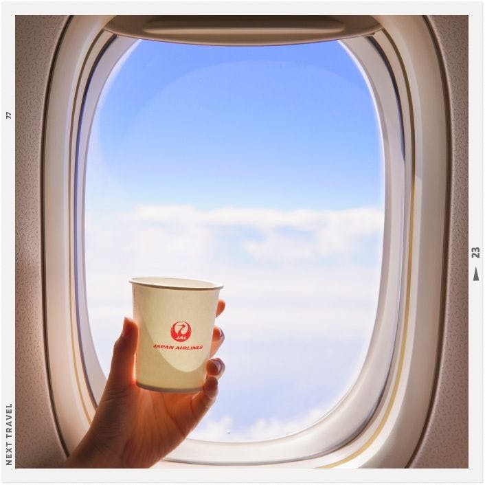 JALの飛行機の窓からの景色とロゴ入りの紙コップ